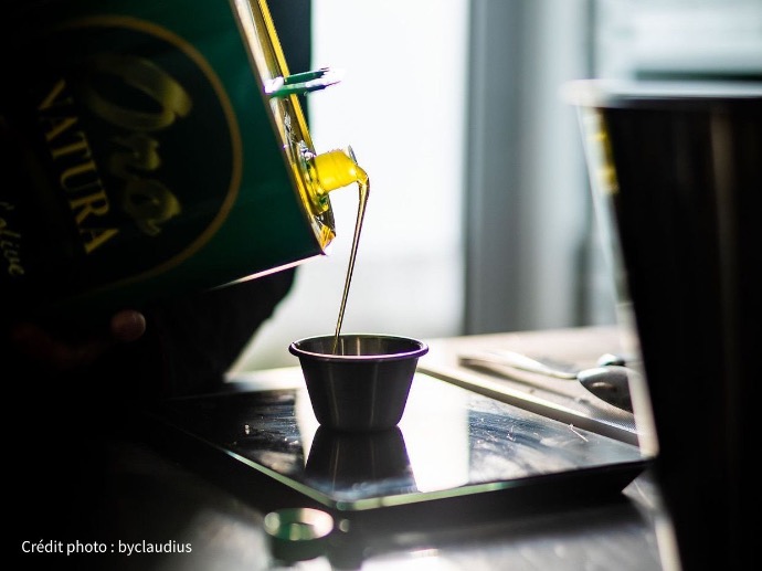 Gros plan sur un filet d'huile d'olive extra vierge coulant d'une bouteille vers un récipient.